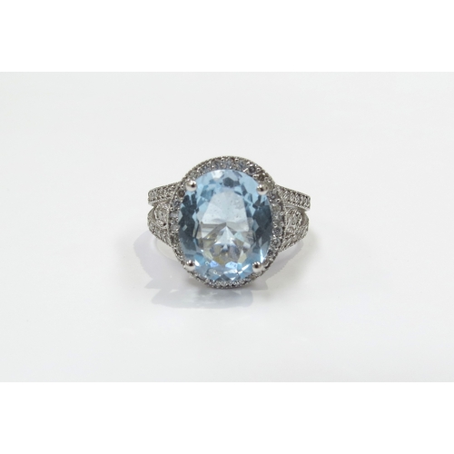 6135 - An 18ct white gold ring centrally set with a large oval topaz framed by diamonds with diamond set op... 