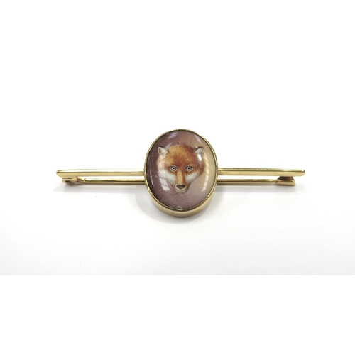 6008 - A gold bar brooch with a painted porcelain oval depicting a foxes head, stamped 750