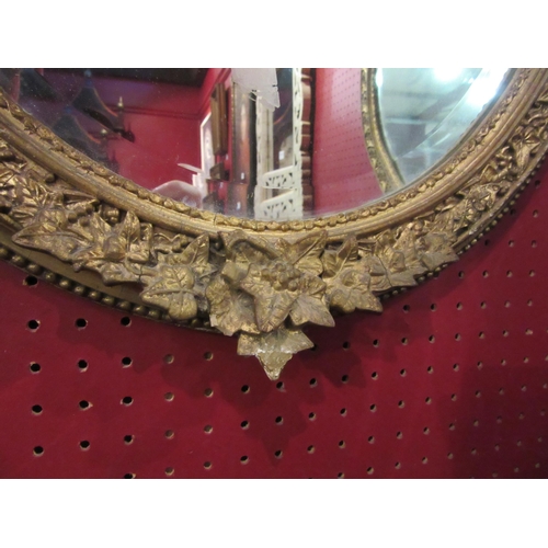 4024 - A pair of early 20th Century oval gilt and gesso wall mirrors with ivy leaf design, each 55cm x 45cm... 