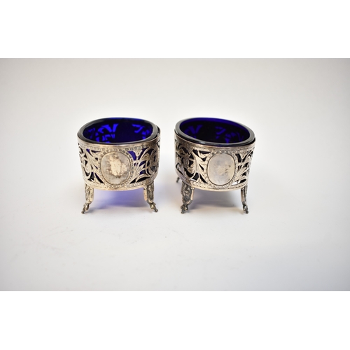 8087 - A pair of 18th Century white metal table salts with blue glass liners pierced floral and acanthus su... 