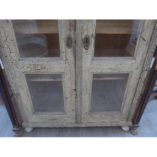 8484 - A French painted pine armoire the two glazed doors with key and shelved interior over turned feet, 1... 