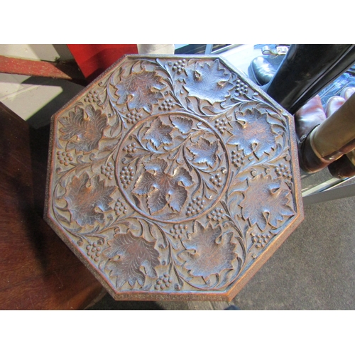 1005 - An Indian hardwood octagonal top fold-up table with carved leaf design, together with an Indian bras... 