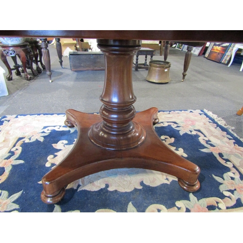 1104 - A circa 1840 flame mahogany round cornered tilt top table over turned bulbous column and plateau bas... 