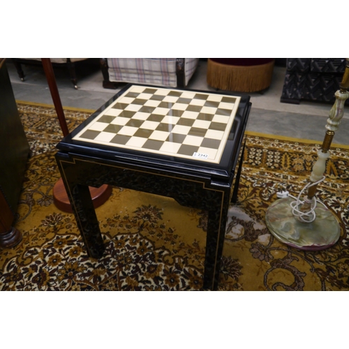 2342 - A black lacquered occasional table which folds over into a chess table, with green baize storage com... 