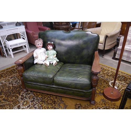 2344 - A 1930's carved oak two seater sofa, green leather