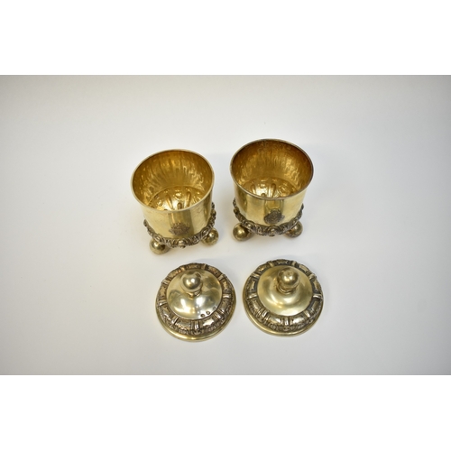 8082 - A pair of 17th/18th Century German silver gilt covered beakers, raised on three ball feet with Armor... 