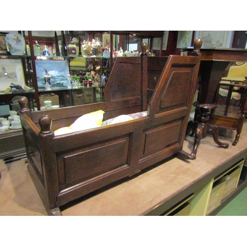 4205 - Circa 1780 a panelled oak cradle with finial decoration raised on sledge feet, 78cm tall x 92cm long... 