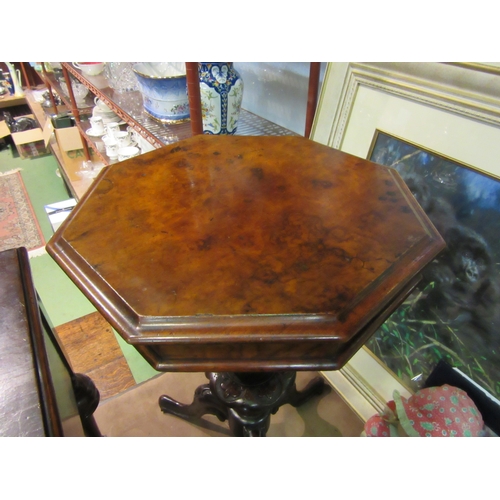 4012 - A Victorian burr walnut octagonal hinged top sewing table over a carved and turned column on a scrol... 