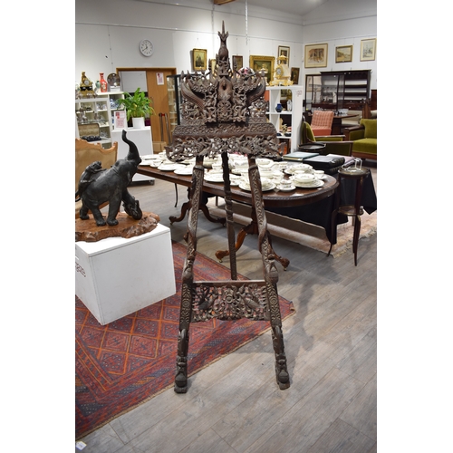 8616 - A highly ornate Thai carved wood easel decorated with flowers, figures and dragons.   77cm x 62cm