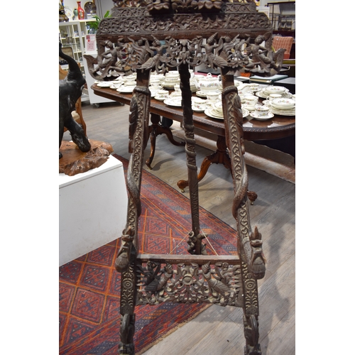 8616 - A highly ornate Thai carved wood easel decorated with flowers, figures and dragons.   77cm x 62cm