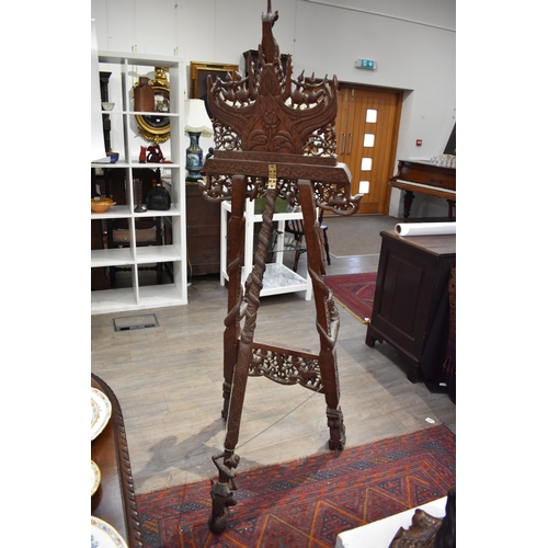 8616 - A highly ornate Thai carved wood easel decorated with flowers, figures and dragons.   77cm x 62cm