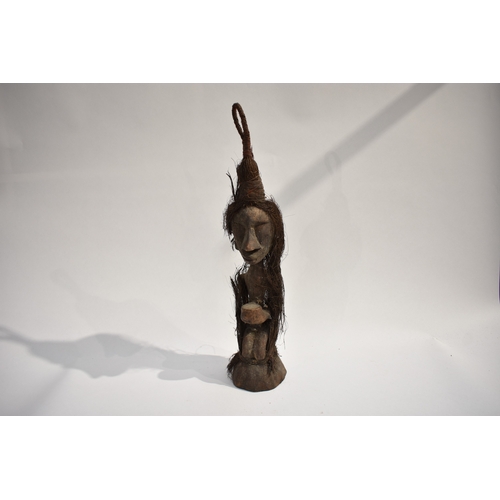 8618 - A Moluccas (Indonesia) type small carved wood ancestor figure, kneeling and holding a bowl with vege... 