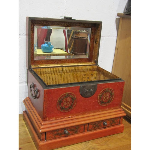 1038 - A Chinese influence red and gilt lacquered wooden jewellery box with mirrored interior and two drawe... 