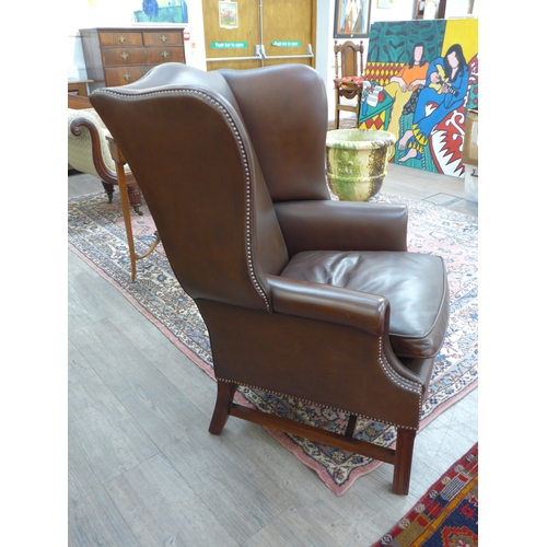 4225 - A modern brown leather armchair with brass stud detail