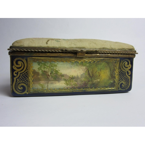 4430 - An enamelled trinket box, hand painted panels of landscapes, enriched with gilt, needlepoint lid