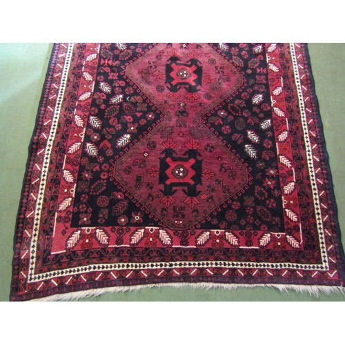 4556 - A Middle-Eastern wool rug, reds and blacks, foliate patterns, 250cm x 164cm