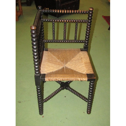 4018 - An ebonised bobbin-turned corner chair with rush seating