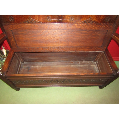 4026 - An 18th Century revival oak box seat settle, the carved panel backrest and scroll arms over a hinged... 