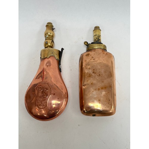 8140 - A copper powder flask of rounded oblong form, together with another with PB initials and foliate des... 