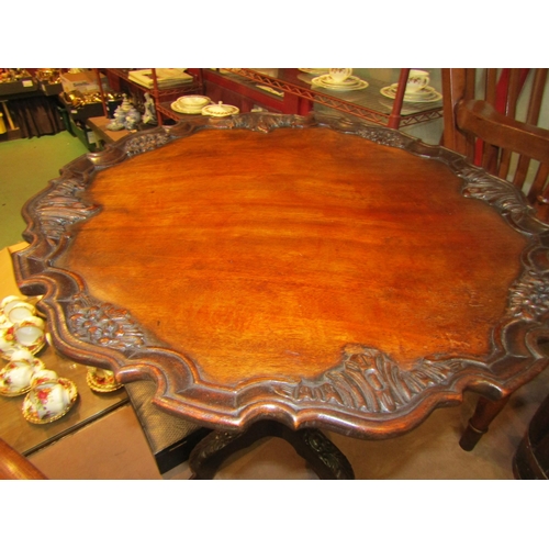 4007 - A Chippendale style carved mahogany pie crust edge revolving tilt-top table on carved tripod base wi... 