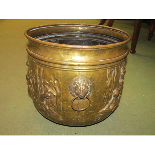 4014 - An embossed brass planter with scenes of children gathered by a fire, lion mask ring handles, 35cm d... 