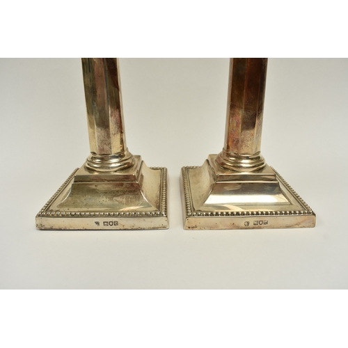 8012 - A pair of late Victorian Reid & Sons silver tall facet Corinthian column candlesticks on cushioned b... 