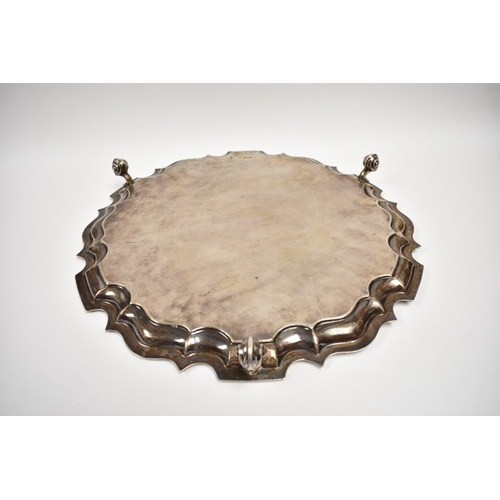8032 - A Thomas Bradbury & Sons Ltd silver salver of piecrust edge form raised on three scroll feet with ce... 