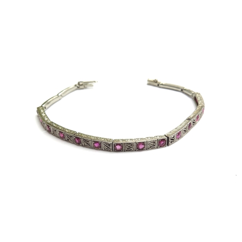 7053 - A white gold and ruby bracelet with seven links of two rubies  alternating with a milgrain panel, sp... 