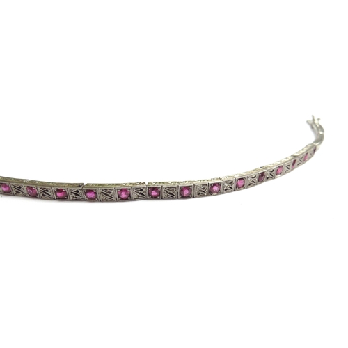 7053 - A white gold and ruby bracelet with seven links of two rubies  alternating with a milgrain panel, sp... 