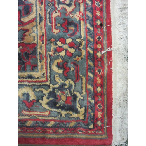 4381 - A large red and blue ground wool rug, central geometric panel and floral design with multiple border... 