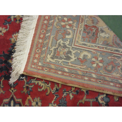 4381 - A large red and blue ground wool rug, central geometric panel and floral design with multiple border... 