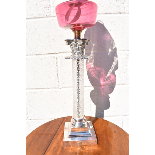 1011 - A late 19th Century French cranberry glass oil lamp with Art Nouveau moulded shade, above cranberry ... 