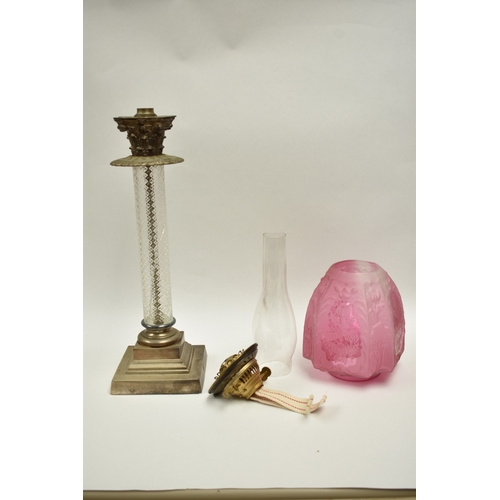 1011 - A late 19th Century French cranberry glass oil lamp with Art Nouveau moulded shade, above cranberry ... 