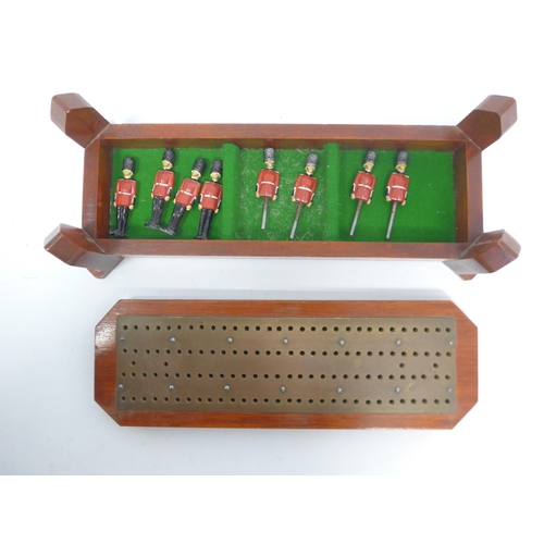 6049 - A wood and brass cribbage board with four figural playing pieces as Royal Guards and four lead figur... 