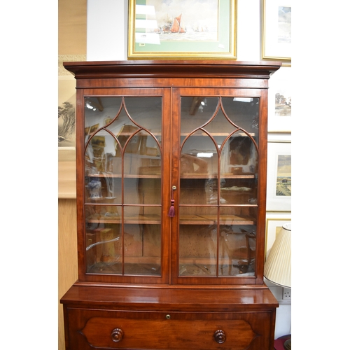 4049 - A Circa 1860 flame mahogany bookcase on base, the cushioned pediment over two astragal glazed doors ... 