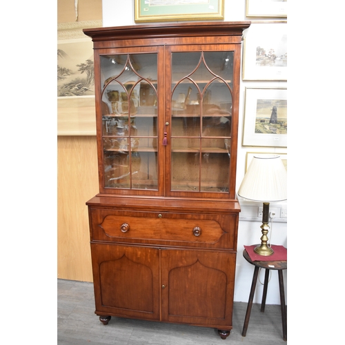 4047 - A Circa 1860 flame mahogany bookcase on base, the cushioned pediment over two astragal glazed doors ... 