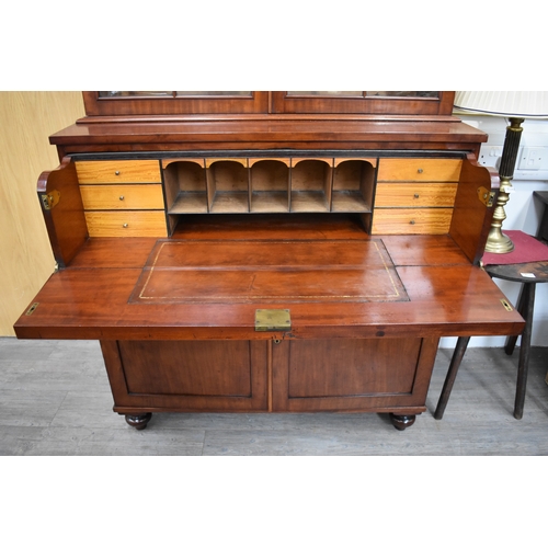 4047 - A Circa 1860 flame mahogany bookcase on base, the cushioned pediment over two astragal glazed doors ... 