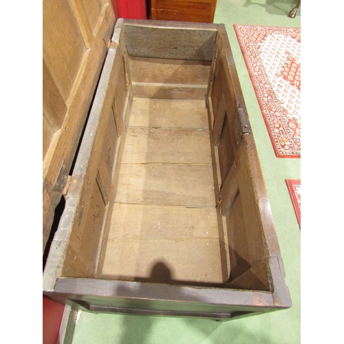 4018 - An 18th Century three panel pegged oak coffer the rising lid over a carved front and channeled munti... 