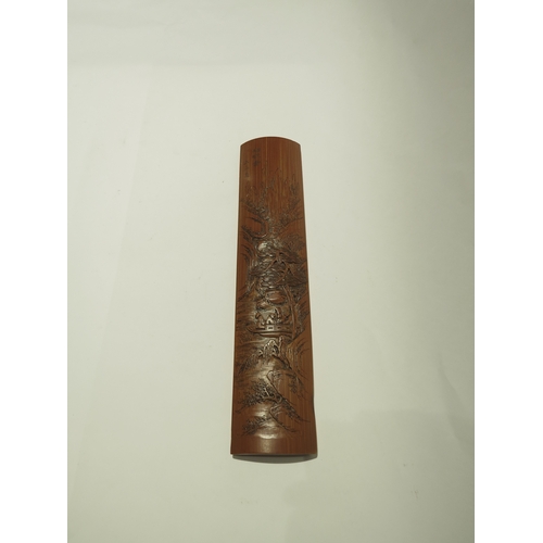 A Chinese bamboo wrist rest carved in low relief with trees in a rocky ...
