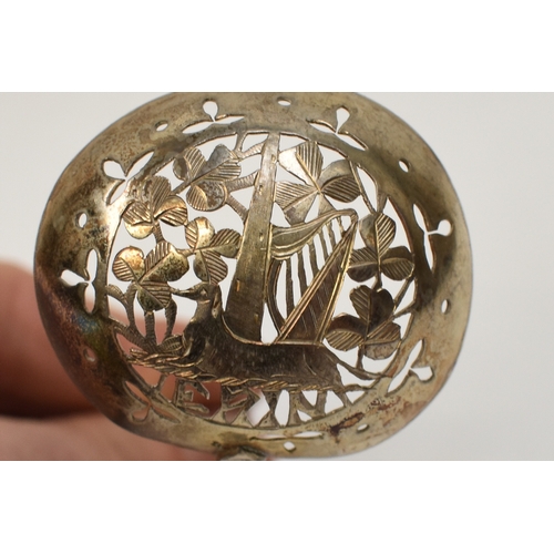 6034 - An Irish Provincial silver sifting spoon by O'Crowley, the bowl decorated with Harp, hound and folia... 