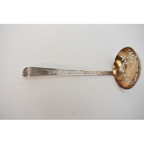 6034 - An Irish Provincial silver sifting spoon by O'Crowley, the bowl decorated with Harp, hound and folia... 