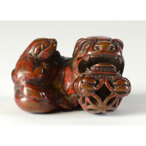 9048 - A lacquered negoro netsuke of a shishi with baby on back, holding a ball in front paws

4cm wide x 3... 