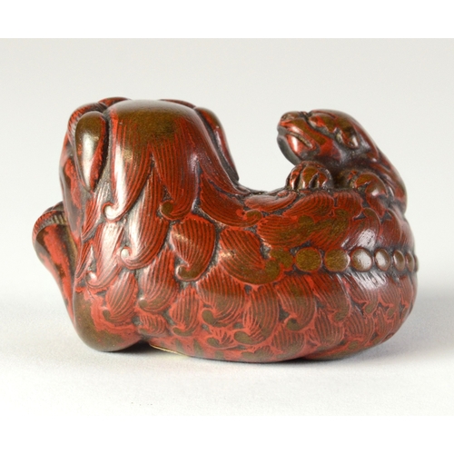 9048 - A lacquered negoro netsuke of a shishi with baby on back, holding a ball in front paws

4cm wide x 3... 