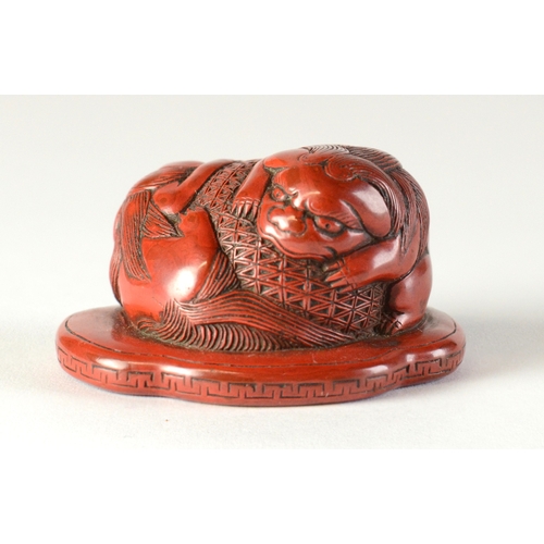 9045 - A red lacquered netsuke in the form of two shishi wrapped around a ball, flat base

3.8cm wide x 3.4... 