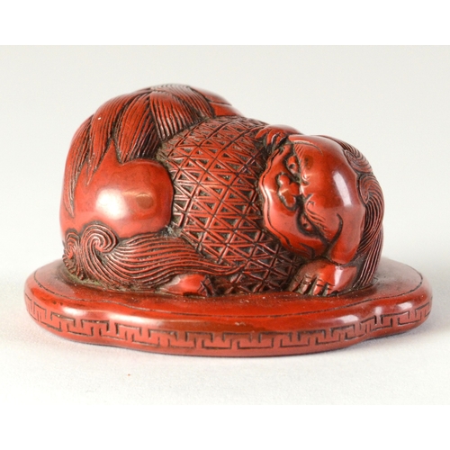 9045 - A red lacquered netsuke in the form of two shishi wrapped around a ball, flat base

3.8cm wide x 3.4... 