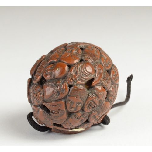 9050 - A carved nut featuring approximately fifty noh masks to include Kitsune, Oni, Okina, Ko-Omote and Ch... 