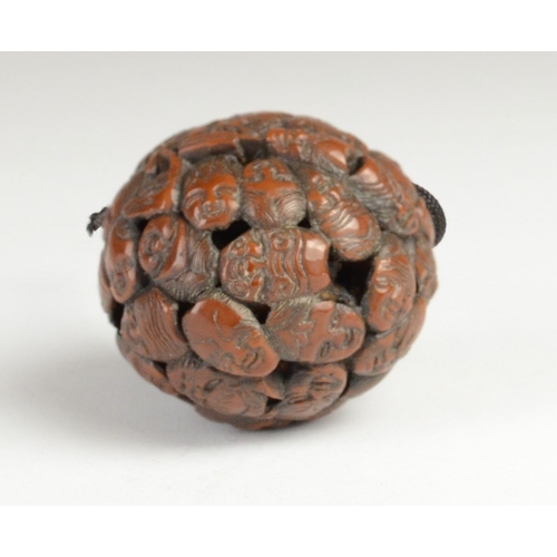 9050 - A carved nut featuring approximately fifty noh masks to include Kitsune, Oni, Okina, Ko-Omote and Ch... 