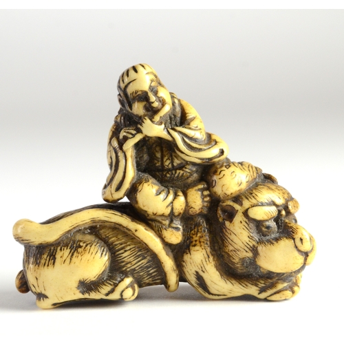 9036 - TOZAN-A stag's horn netsuke of Monju Bosatsu on a lion's back, playing the flute- signed Tozan in ov... 