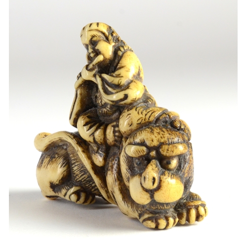 9036 - TOZAN-A stag's horn netsuke of Monju Bosatsu on a lion's back, playing the flute- signed Tozan in ov... 