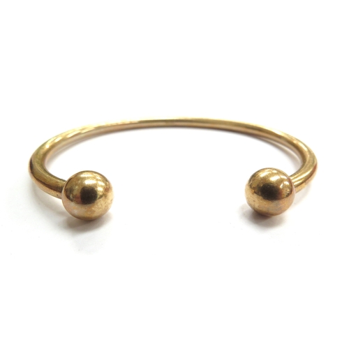 6024 - A 9ct gold bangle with ball terminals, 24.2g